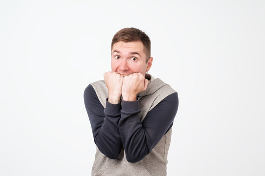 European man covering his mouth with both hands, looking shocked.