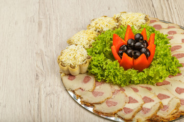 Meat sliced on a mirror dish decorated with verdure.