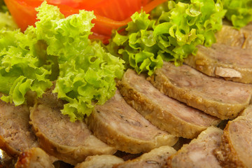 Meat sliced on a mirror dish decorated with verdure.