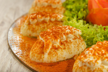 Eggs with mayonnaise on a platter with herbs and vegetable decoration.
