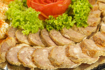 Meat sliced on a mirror dish decorated with verdure.