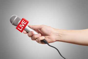 Male hand holding a microphone, isolated on grey background