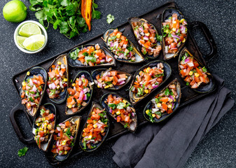 PERUVIAN FOOD. Choros a la chalaca. Big mussels, choros zapatos seasoned with purple onion, tomatoes, corn and lemon. Top view, black background. Traditional peruvian dish