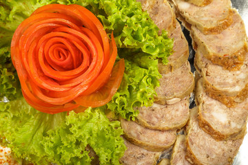 Meat sliced on a mirror dish decorated with verdure.