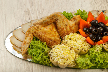 Dish from tartlets and chicken wings with the presence of lettuce leaves.