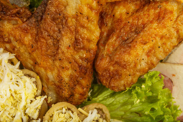 Dish from tartlets and chicken wings with the presence of lettuce leaves.
