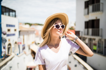 Outdoor fashion portrait girl wearing hat, trendy sunglasses sitting on handrail, amazing view of city from the top