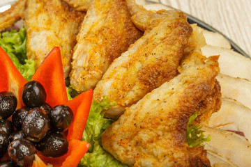 Dish from tartlets chicken wings and meat sliced with the presence of lettuce leaves.
