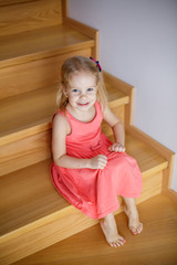 Portrait of little cute girl smiling on stairs in cozy room