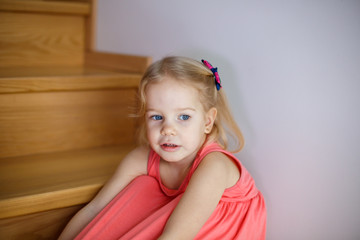 Portrait of little cute girl smiling on stairs in cozy room
