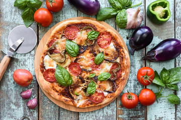Homemade rustic pizza. Aubergine pizza with tomato and basil surrounded with raw ingredients on old...