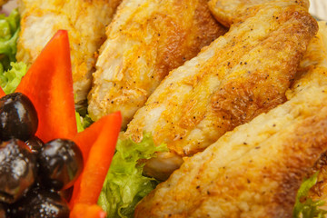 Dish from tartlets chicken wings and meat sliced with the presence of lettuce leaves.