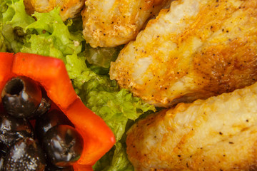 Dish from tartlets and chicken wings with the presence of lettuce leaves.