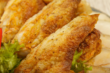 Dish from tartlets and chicken wings with the presence of lettuce leaves.