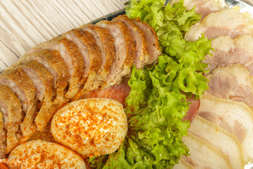Meat sliced on a mirror dish decorated with verdure.