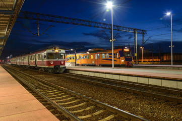 Fototapeta na wymiar Dworzec kolejowy i pociągo wieczorem i nocą oświetlone lampami.