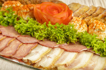 Meat sliced on a mirror dish decorated with verdure.