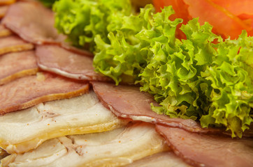 Meat sliced on a mirror dish decorated with verdure.