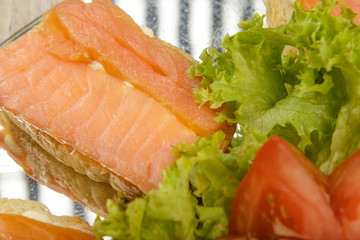 Dish of sandwiches with red fish tomato and greens.