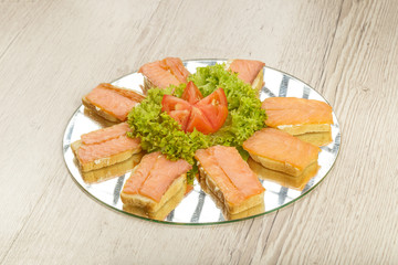 Dish of sandwiches with red fish tomato and greens.