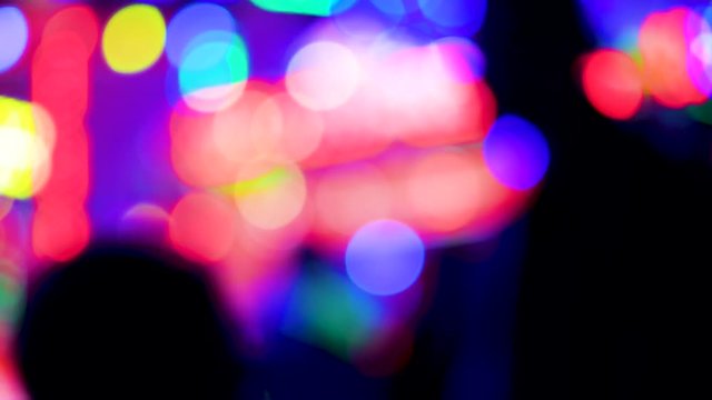 Defocused funny atmosphere at the amusement park in megapolis with multiple colorful lights