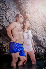 a man with a woman standing near a rock knee-deep in water. The concept of a romantic pastime.