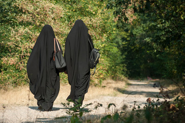 Rear view of women in burqa walking in forest