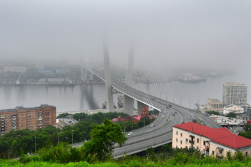 Fototapeta premium Russia, the bridge across the Golden horn bay in Vladivostok in strong fog im summer