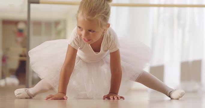 Portrait of a beautiful very young girl, in a dance school wearing a white tutu, she trains alone to learn new dance steps. Concept of: ambition, education, elegance and love for the dance&hellip;