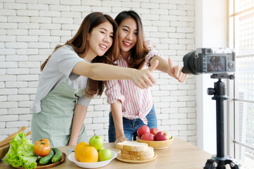 Two young asian woman food bloggers talking while recording video, vlog concept, people and technology communication