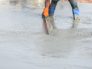 People plastering cement skimming the concrete surface from Pouring ready-mixed concrete after placing steel reinforcement to make the road.