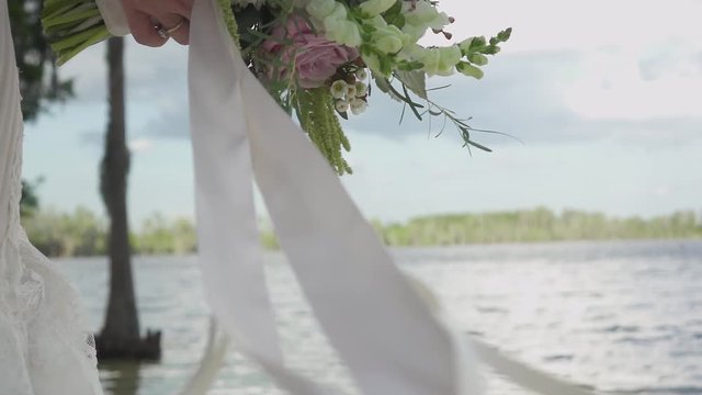 A bride's floral bouquet ribbon flowing in the wind.