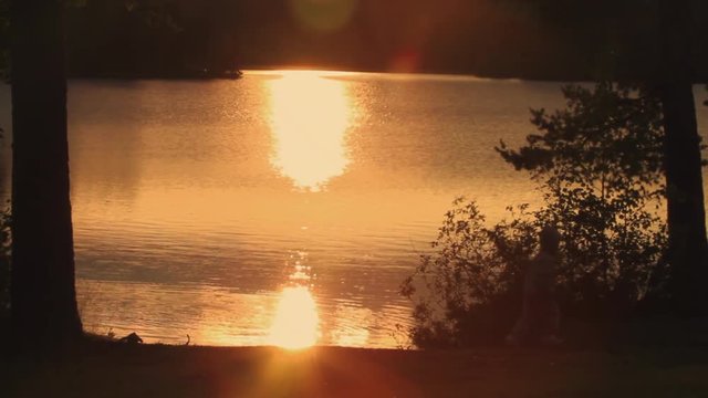 Kid Following Mother Along River at Sunset Lens Flare
