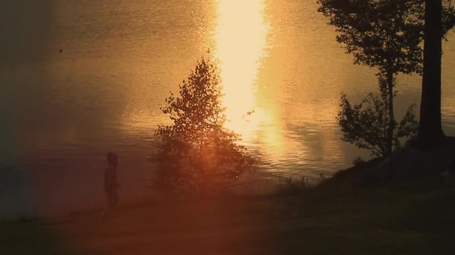 Child Following Mom Along Water at Sunset
