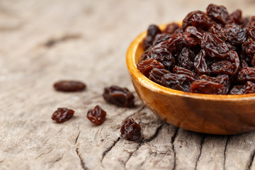 Raisins in a wooden bowl on the old wooden table