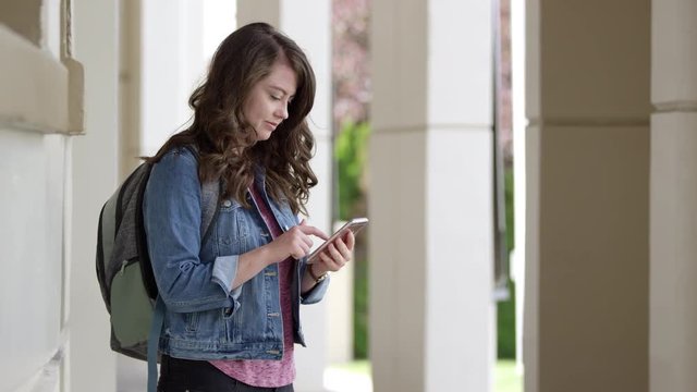 Young woman typing on smartphone using app then walks away when finished.
