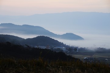 Rural town and mountains are covered with dense fog
