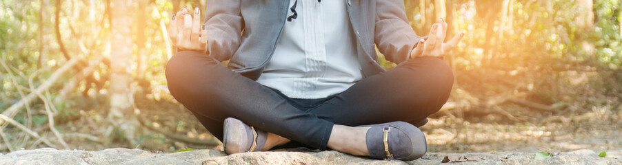 A young businessman is meditating in the forest with peace.