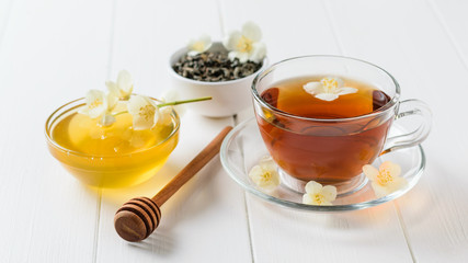 Freshly prepared jasmine tea with Jasmine flowers and honey on a rustic white table.