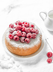 Simple sponge cake with powdered sugar and fresh raspberries on a light background. Summer berry dessert. Flat lay