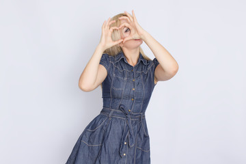 Studio portrait of a blonde woman in a denim dress. Girl posing on white background