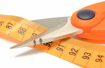 Scissors cutting tape measure on white background, slimming concept