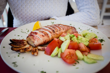 Delicious grilled calamari and vegetables, greek salad, freshly made in Santorini, Greece.
