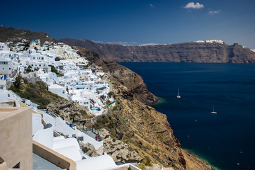 Fototapeta na wymiar Gourgeous view from white walled town of Oia in Santorini, Greece, with ocean, cliffs and caldera of Santorini in the background.