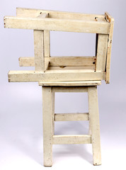 Wooden chair with white backdrop.