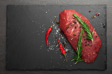 fresh raw meat with rosemary on black slate, on dark background, steak Ribeye