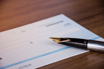 Cheque book and pen isolated on wood background.