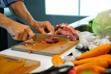 A man prepares food, cuts meat with a knife