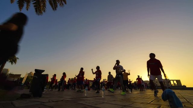 Doha, Qatar, 2 December 2016 - People doing early morning Zomba exercises on cornice with sunrise in the background