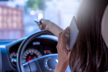 Young woman in car, hand using remote control to open the automatic gate while phoning and leaving...